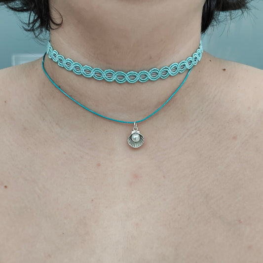 Elevate your style with our stunning Choker Necklace! The aqua lace ribbon, paired with a delicate polyester strand, creates a unique and elegant look. Adorned with a charming clam shell and an acrylic white pearl bead, this necklace exudes sophistication and grace. Stand out from the crowd with this must-have accessory.