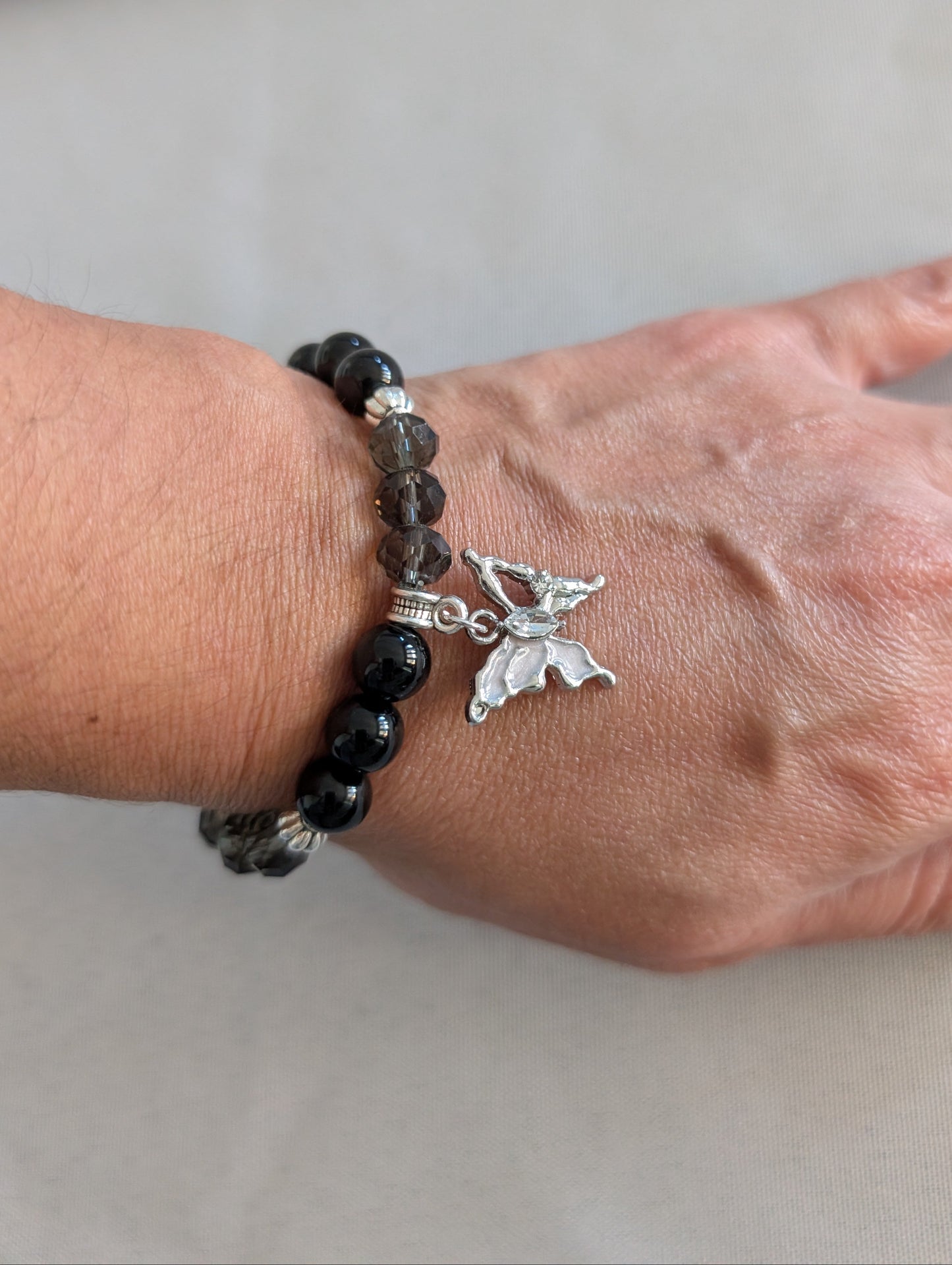 Elevate your everyday style with this stunning elastic bracelet featuring lustrous 8mm black beads paired with shimmering crystal and glass accents. Delicate silver spacer beads guide your eye to the centerpiece—an elegant silver butterfly charm that symbolizes transformation and grace. Lightweight at just 0.53 oz, this versatile piece transitions seamlessly from casual to sophisticated, making it the perfect accessory for any occasion. The elastic design ensures a comfortable, adjustable fit for all wrist 