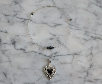 This elegant memory wire choker combines timeless style with modern sophistication. Featuring a striking black stainless steel heart pendant accented with lustrous black beads, it adjusts perfectly to fit neck sizes 4 to 4.5 inches. The durable .025" wire construction ensures lasting wear without losing its shape, while the lightweight design at just 0.28 oz makes it comfortable for all-day elegance. Whether layered with other pieces or worn solo, this versatile choker adds an instant touch of charm to any 