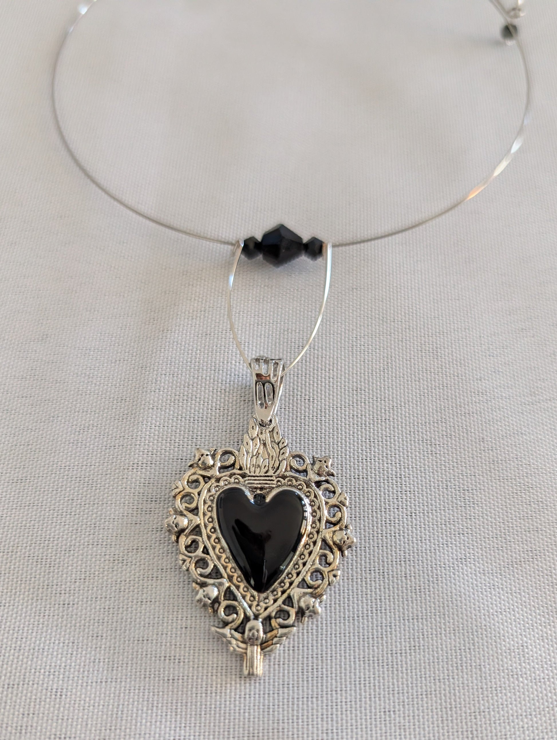 This elegant memory wire choker combines timeless style with modern sophistication. Featuring a striking black stainless steel heart pendant accented with lustrous black beads, it adjusts perfectly to fit neck sizes 4 to 4.5 inches. The durable .025" wire construction ensures lasting wear without losing its shape, while the lightweight design at just 0.28 oz makes it comfortable for all-day elegance. Whether layered with other pieces or worn solo, this versatile choker adds an instant touch of charm to any 
