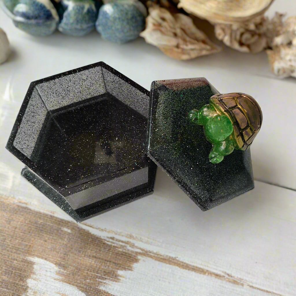 Add a playful touch to your home decor with this Knickknack! The resin hexagon trinket box features a turtle lid and is the perfect size for storing small treasures. With dimensions of 2.5 x 3 x 1 inches and weighing only 3.4 ounces, it's a quirky and lightweight addition to any room.