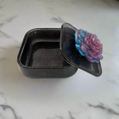 Elevate your jewelry collection with this stunning Knickknack jewelry box. Featuring a flower lid and made of durable resin, this box measures 5 x 5 inches and has a depth of 1.5 inches, making it perfect for large pieces. Weighing only 14 oz, it's also lightweight and easy to transport. Transform your dressing table and protect your precious pieces with this beautiful box.