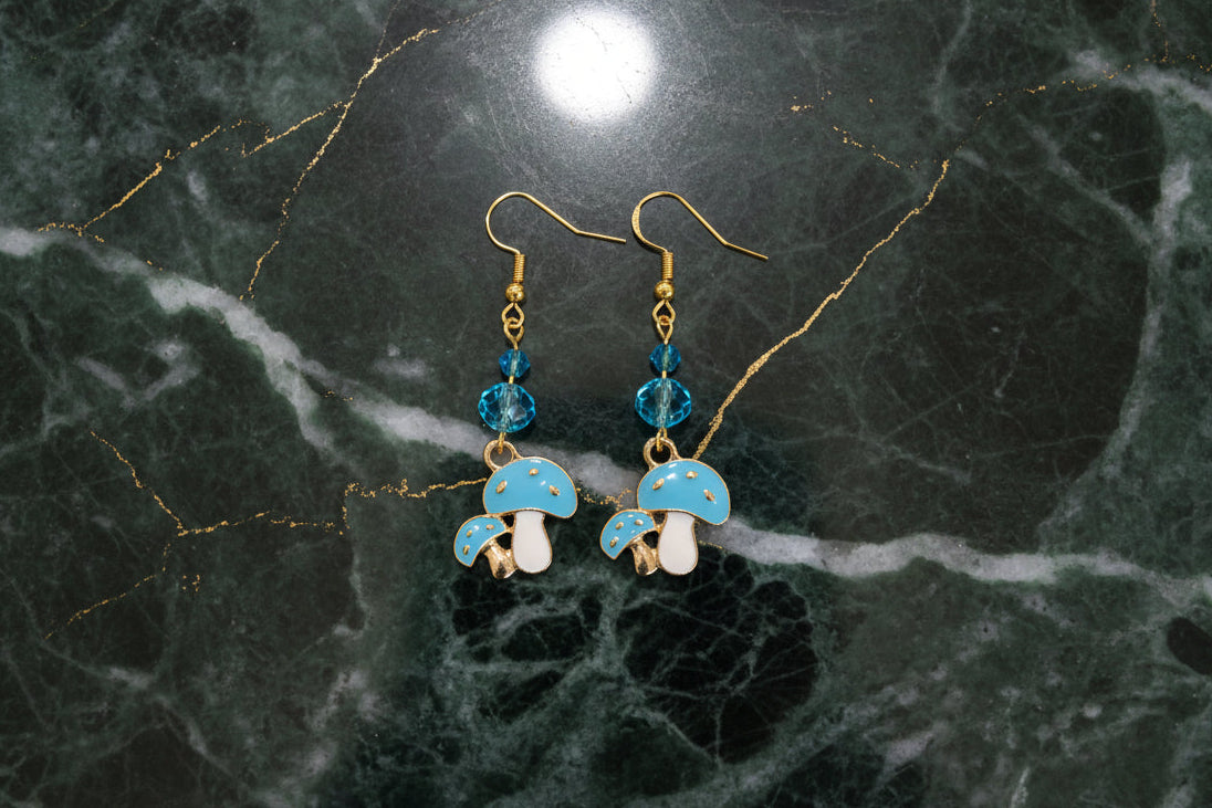 Enchanting mushroom earrings featuring delicate crystal beads nestled on lustrous gold plated hooks. Each earring measures approximately 2 inches, striking the perfect balance between statement-making and wearable elegance. At just 0.15 oz per pair, these lightweight beauties won't weigh you down, making them ideal for all-day wear. The shimmering gold plating catches the light beautifully, while the crystal accents add a touch of sparkle and sophistication. 