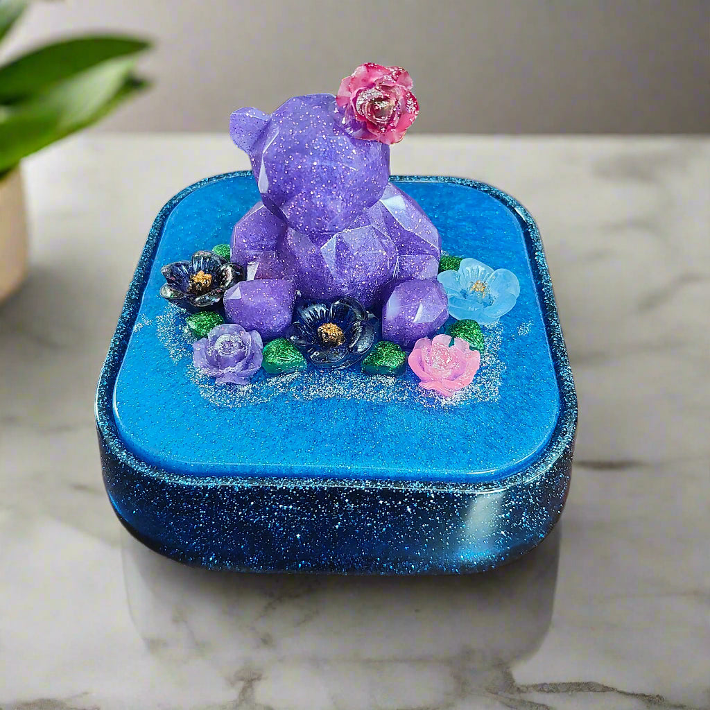 Elevate your jewelry storage with our Knickknack - Large resin square box! Featuring a charming bear and flowers lid, it adds a whimsical touch to any room. Boasting ample space for your precious items, it's the perfect blend of function and beauty. Upgrade to this stunning jewelry box today!