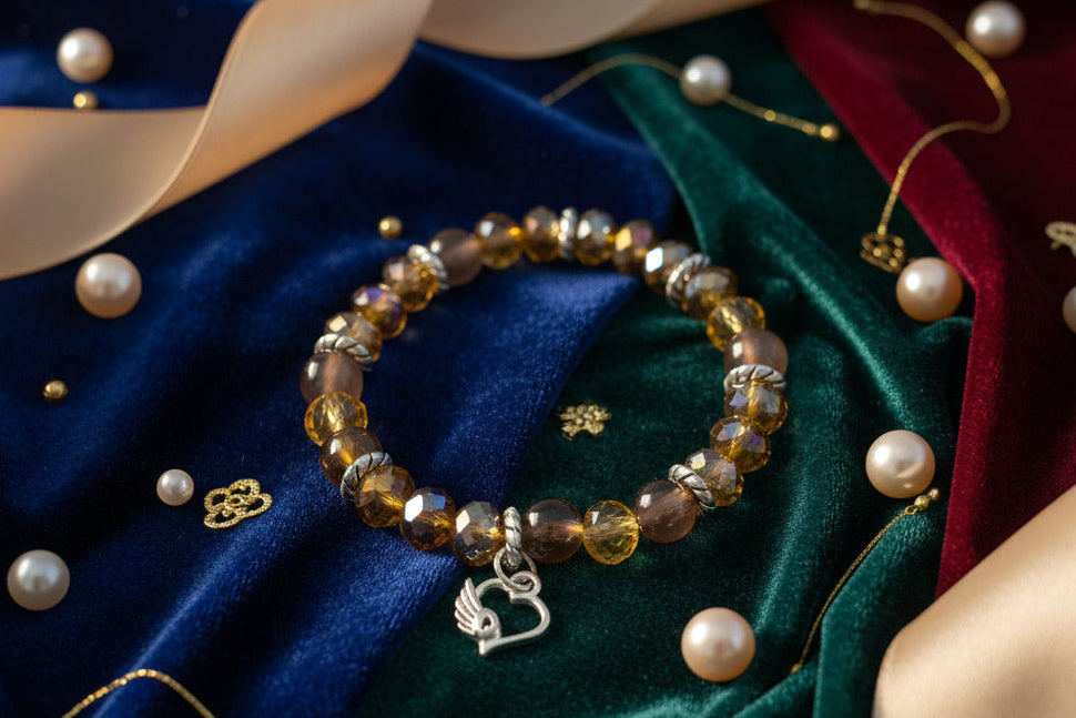 Express your heart with this warm and radiant elastic bracelet that combines rich brown and gold tones with timeless sentiment. Featuring 8mm brown and gold beads interspersed with sparkling crystal and glass accents, silver spacers, and a delicate silver heart charm, this piece speaks to both style and emotion. The elastic band stretches effortlessly to fit any wrist, requiring no clasps or adjustments—just slip it on and go. Weighing a comfortable 0.60 oz, it's substantial enough to feel quality yet light