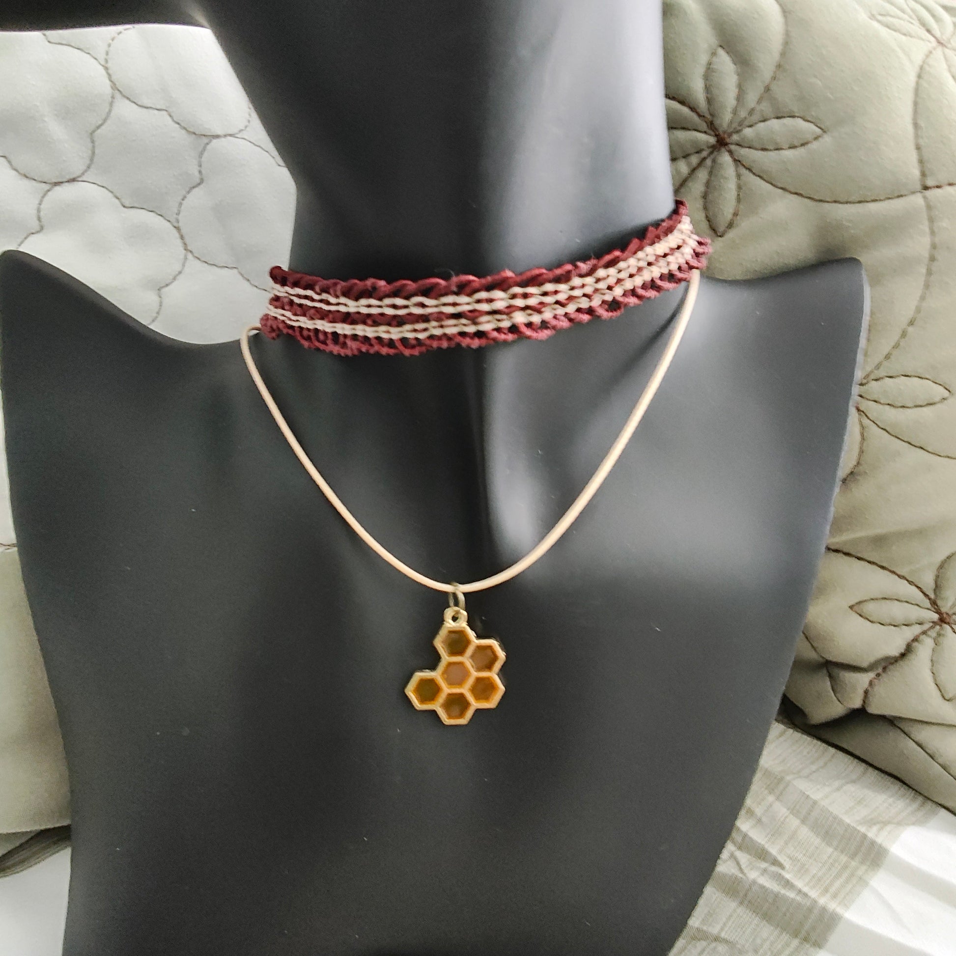 Add a touch of quirkiness to your outfit with our brown lace choker featuring a playful honey comb charm. Made with a durable polyester strand, it's both stylish and versatile for any occasion. Don't be afraid to let your personality show with this unique necklace!