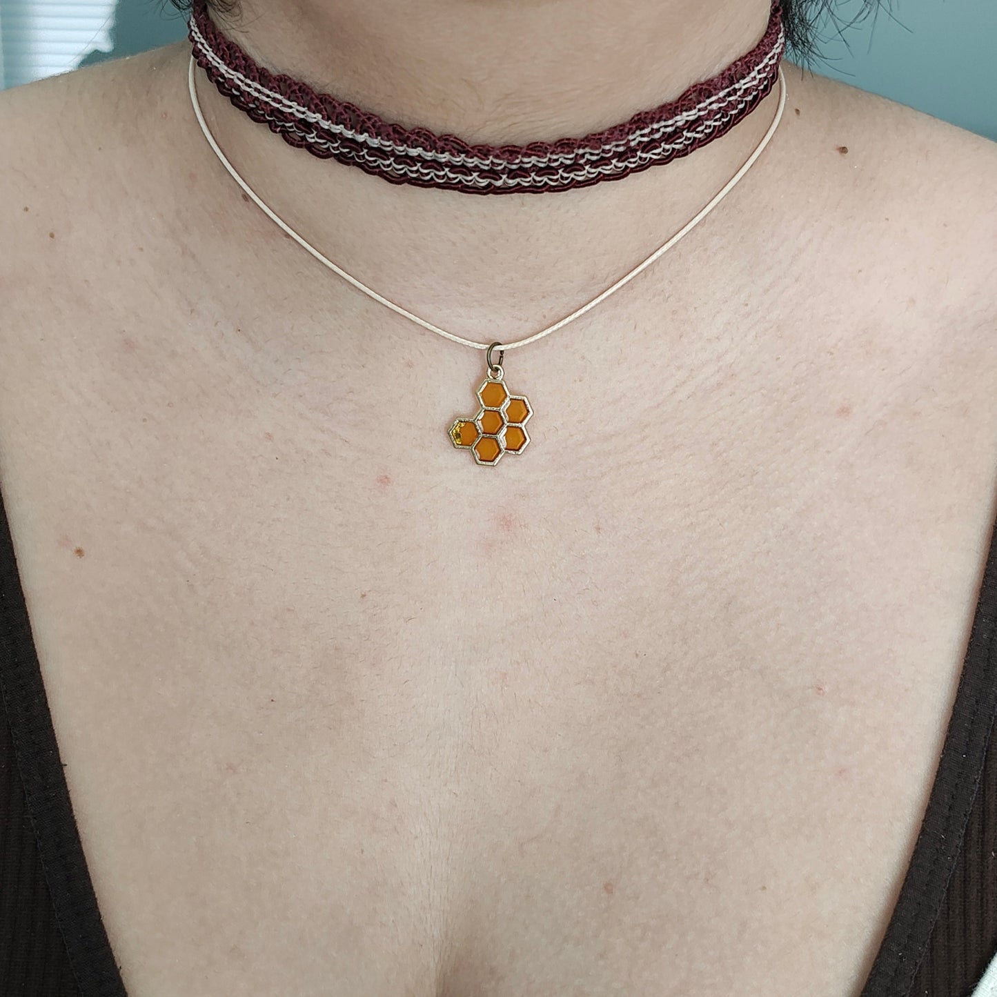 Add a touch of quirkiness to your outfit with our brown lace choker featuring a playful honey comb charm. Made with a durable polyester strand, it's both stylish and versatile for any occasion. Don't be afraid to let your personality show with this unique necklace!