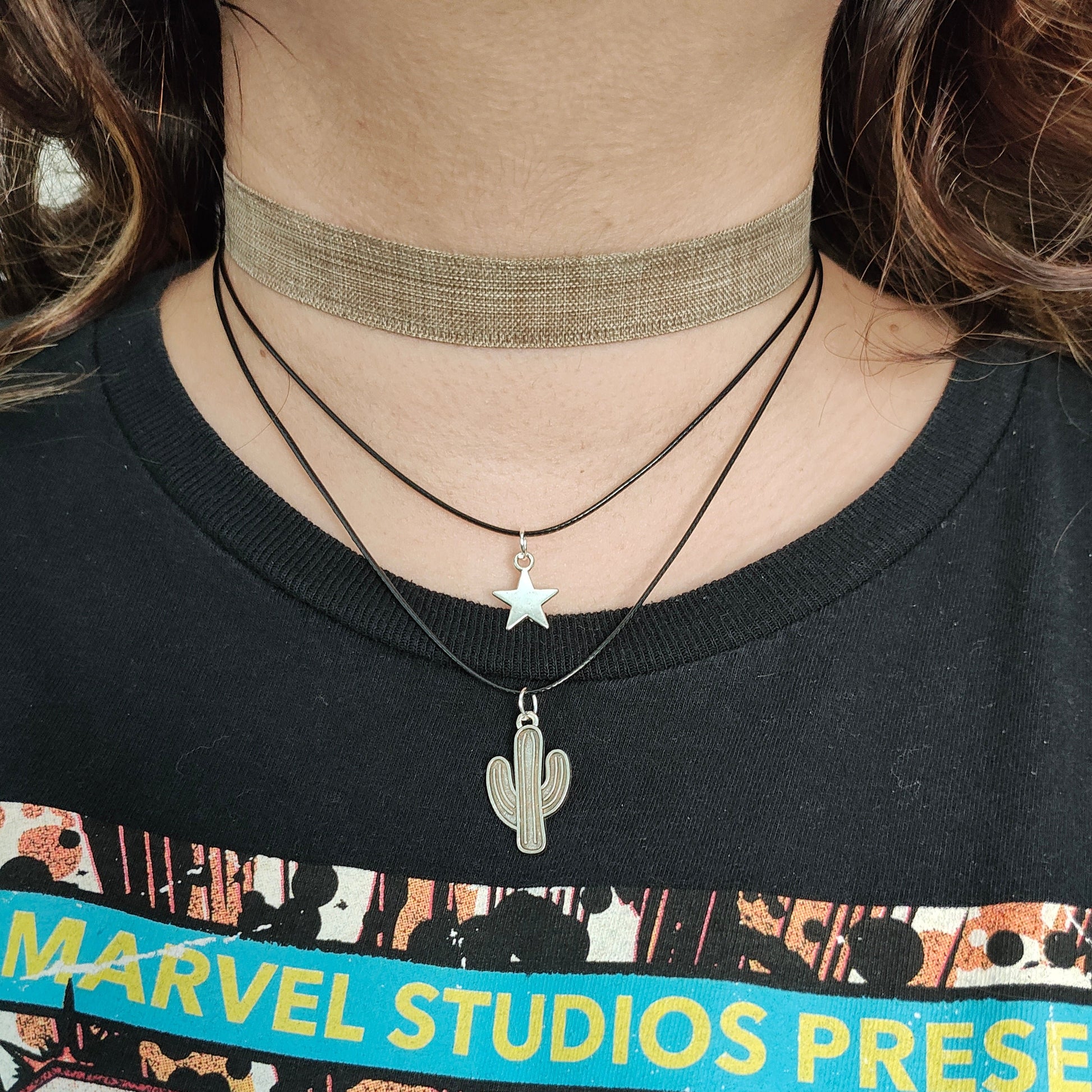Elevate your style with this trendy and unique choker necklace. The brown ribbon adds a touch of warmth while the silver star and cactus charms add a playful and chic touch. Made with two polyester strands for durability and comfort. A must-have addition to your jewelry collection.