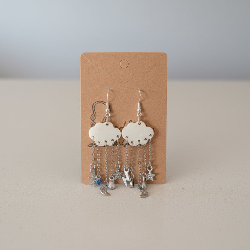 Pair of cloud-shaped earrings with chain details on a cardboard backing.
