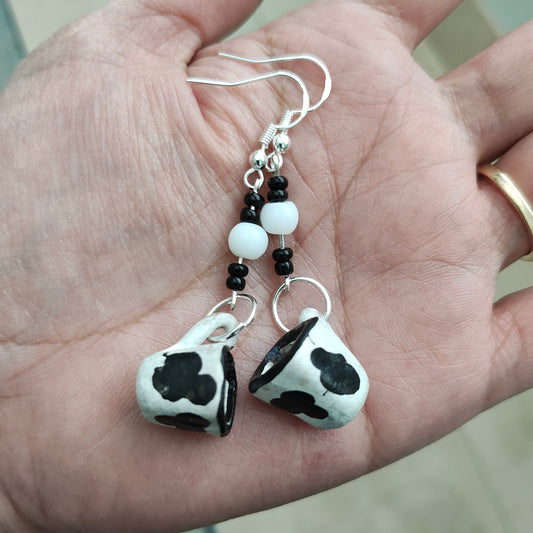 Spice up your style with these quirky cow mug earrings! Made of ceramic, these unique earrings feature a playful cow print design with beads on silver hooks. Lightweight and measuring 2.5 inches long, they're the perfect addition to any fun-loving fashionista's collection. (Moo-vingly cute!)