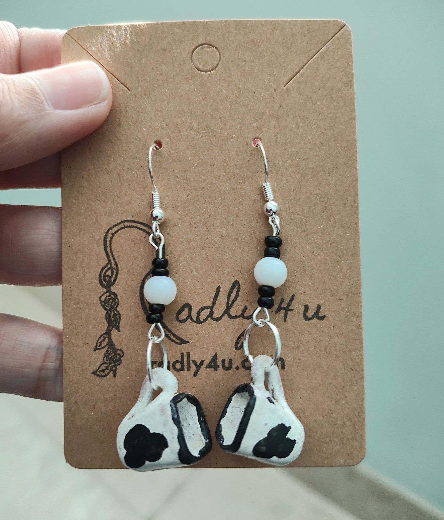 Spice up your style with these quirky cow mug earrings! Made of ceramic, these unique earrings feature a playful cow print design with beads on silver hooks. Lightweight and measuring 2.5 inches long, they're the perfect addition to any fun-loving fashionista's collection. (Moo-vingly cute!)