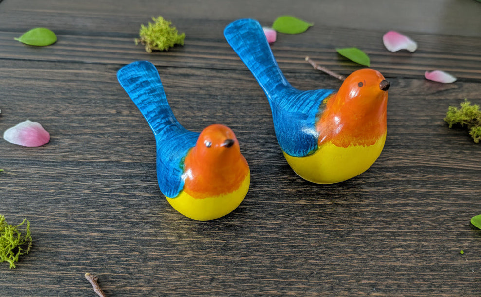 Two colorful bird figurines on a wooden surface