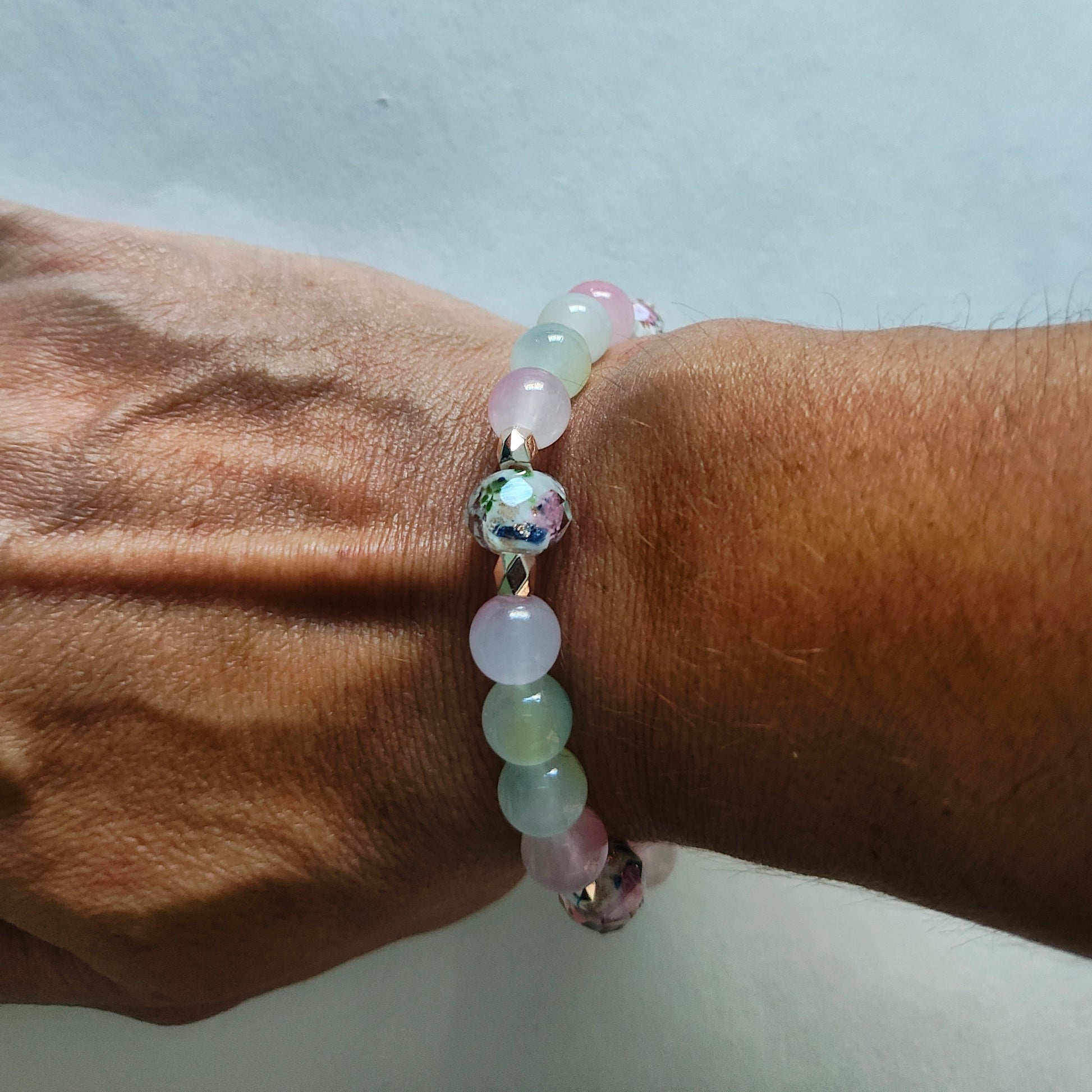 This stunning Bracelet features 9mm rose gold sand lampwork beads, complemented by 8mm pink and green glass beads. Adorned with gold rose spacer beads, the elastic design ensures a comfortable and secure fit. Elevate your style with this beautifully crafted piece.