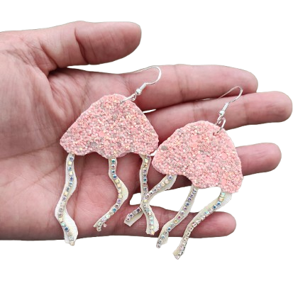 Faux Leather Jelly Fish Earrings! Crafted with a silver hook, the shimmering pink glitter and faux leather design will make you stand out in any event. Embrace the beauty of the sea with these stunning earrings.