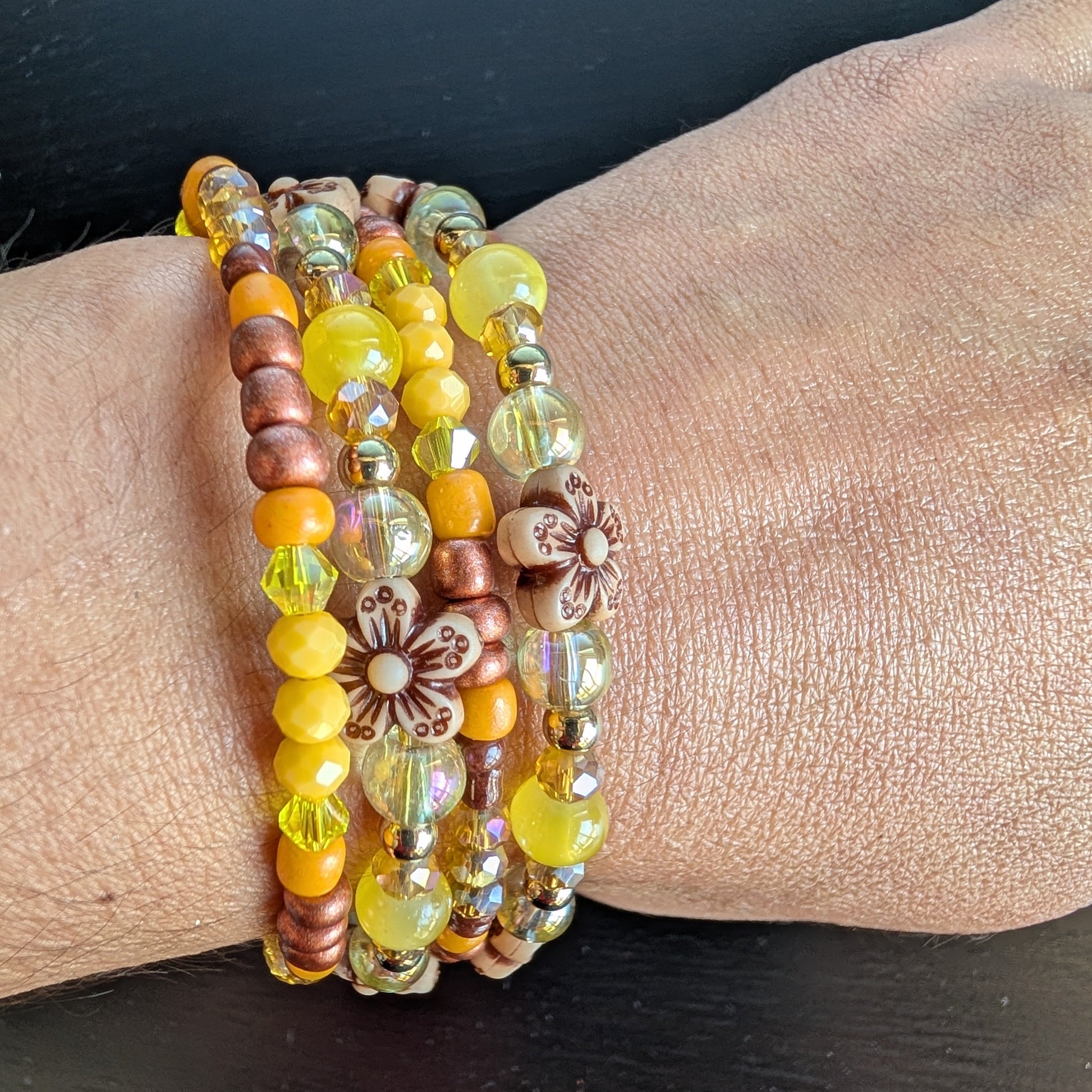 Brighten your style with this stunning memory wire bracelet featuring four coils of vibrant yellow beads accented by yellow and bronze spacer beads. Its flexible design ensures a comfortable fit for any wrist, while the floral-inspired arrangement adds a cheerful, handcrafted touch. Perfect for elevating everyday outfits with a splash of sunny elegance and subtle metallic charm.