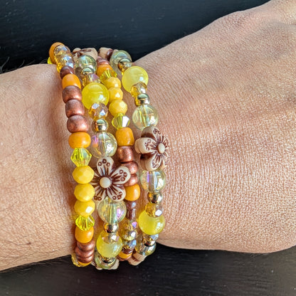 Brighten your style with this stunning memory wire bracelet featuring four coils of vibrant yellow beads accented by yellow and bronze spacer beads. Its flexible design ensures a comfortable fit for any wrist, while the floral-inspired arrangement adds a cheerful, handcrafted touch. Perfect for elevating everyday outfits with a splash of sunny elegance and subtle metallic charm.