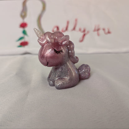 This whimsical resin unicorn is hand-crafted with glossy epoxy resin and detailed with vibrant acrylic paints. Its smooth, glass-like finish captures light beautifully, making it a charming little companion on your desk or shelf.