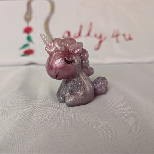 This whimsical resin unicorn is hand-crafted with glossy epoxy resin and detailed with vibrant acrylic paints. Its smooth, glass-like finish captures light beautifully, making it a charming little companion on your desk or shelf.
