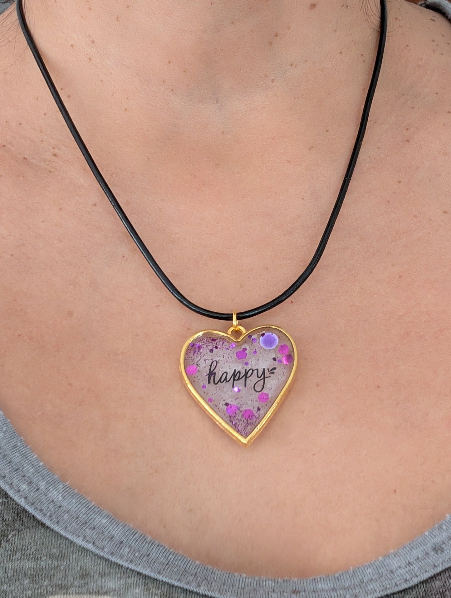 Fall in love with this 18 inch resin and glitter gold heart pendant necklace! The vibrant charm hangs beautifully on a black 2mm leather cord, adding a touch of happiness to any outfit. With a weight of only 0.2 oz, you'll hardly feel it's there. Don't miss out on this unique and stylish piece!