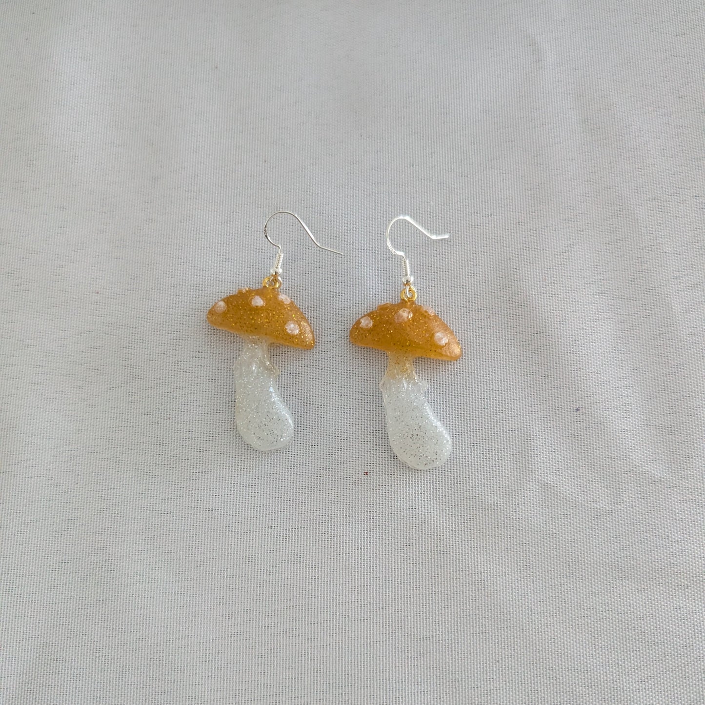 Mushroom-shaped earrings on a light gray background