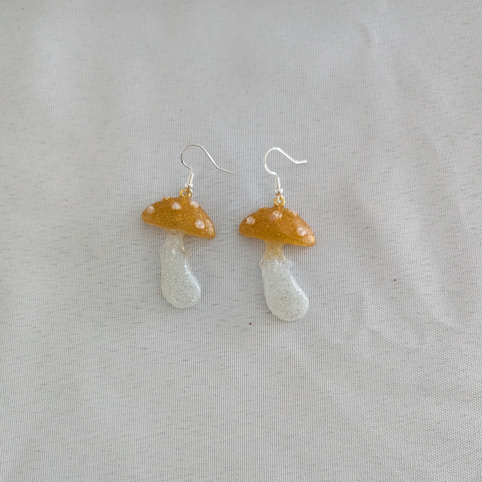 Mushroom-shaped earrings on a light gray background