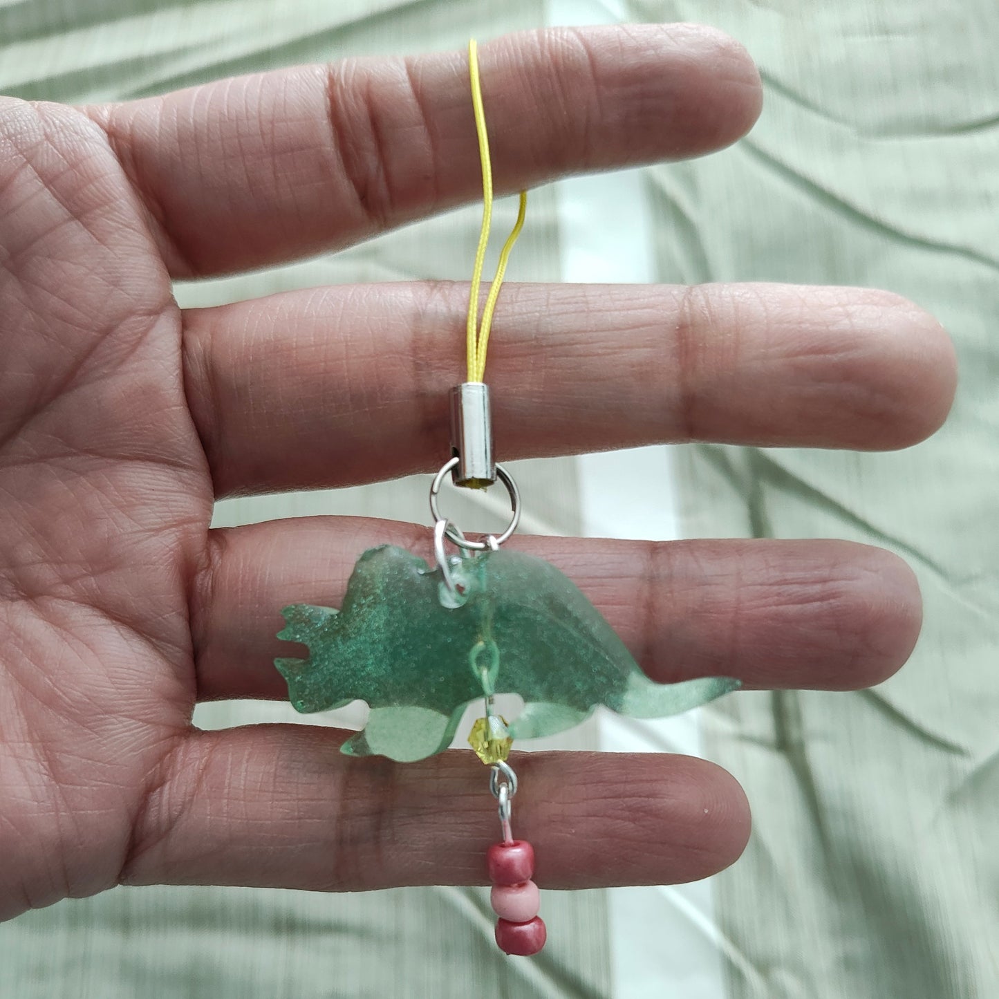 Add some prehistoric charm to your phone with our Triceratops resin dinosaur charm, adorned with colorful beads. Stand out from the herd and protect your phone in style. (No need to be a fossil to appreciate this cute accessory!)