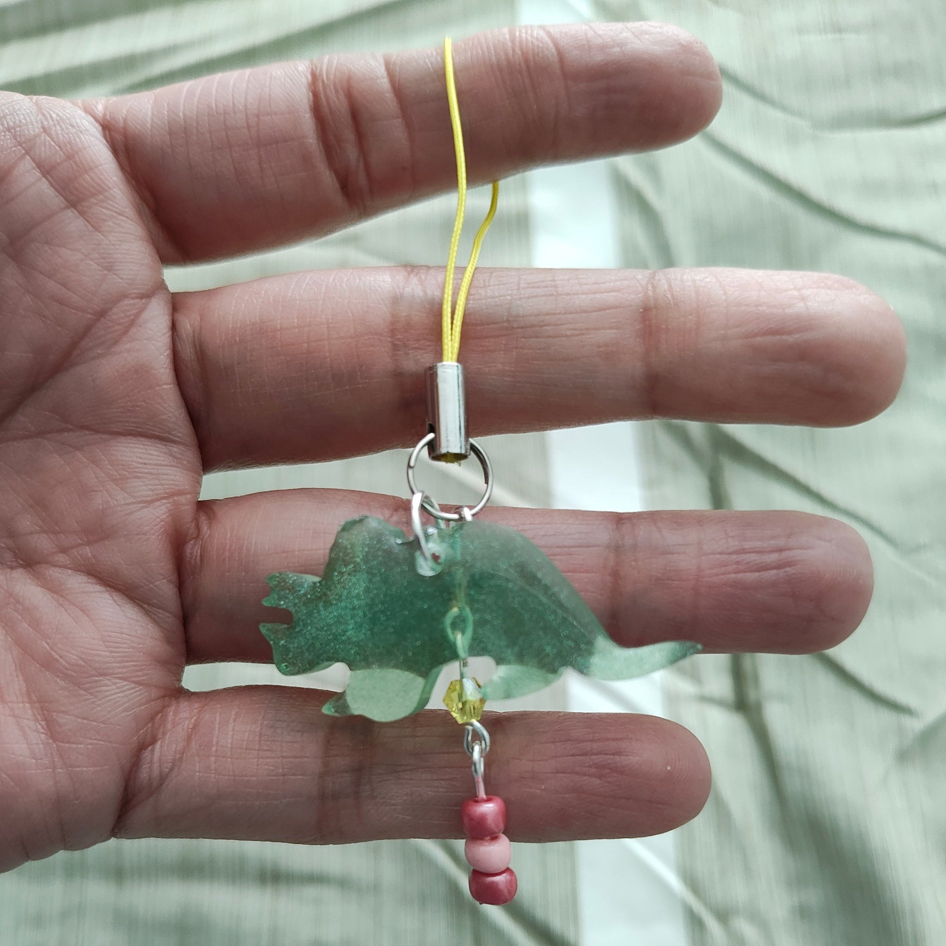 Add some prehistoric charm to your phone with our Triceratops resin dinosaur charm, adorned with colorful beads. Stand out from the herd and protect your phone in style. (No need to be a fossil to appreciate this cute accessory!)