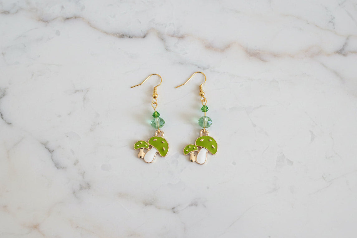 Enchanting mushroom earrings featuring delicate crystal beads nestled on lustrous gold plated hooks. Each earring measures approximately 2 inches, striking the perfect balance between statement-making and wearable elegance. At just 0.15 oz per pair, these lightweight beauties won't weigh you down, making them ideal for all-day wear. The shimmering gold plating catches the light beautifully, while the crystal accents add a touch of sparkle and sophistication. 