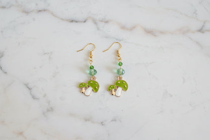 Enchanting mushroom earrings featuring delicate crystal beads nestled on lustrous gold plated hooks. Each earring measures approximately 2 inches, striking the perfect balance between statement-making and wearable elegance. At just 0.15 oz per pair, these lightweight beauties won't weigh you down, making them ideal for all-day wear. The shimmering gold plating catches the light beautifully, while the crystal accents add a touch of sparkle and sophistication. 