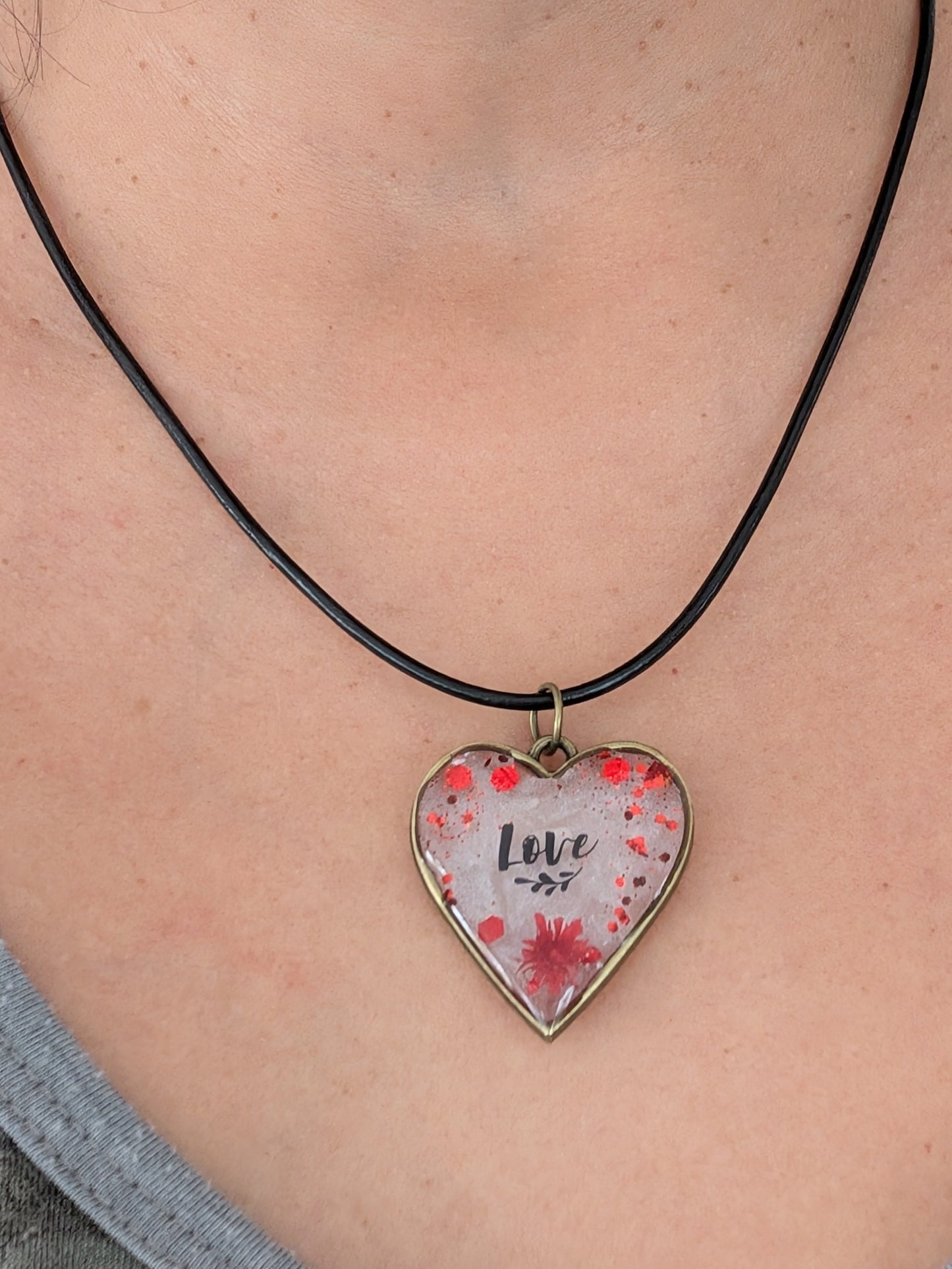 This stunning necklace features an 18 inch black leather cord with a resin and flowers bronze heart pendant. The extension chain allows for a customizable fit. Weighing only 0.2 oz, it's a lightweight and stylish addition to any outfit. Show your love and creativity with this unique necklace.