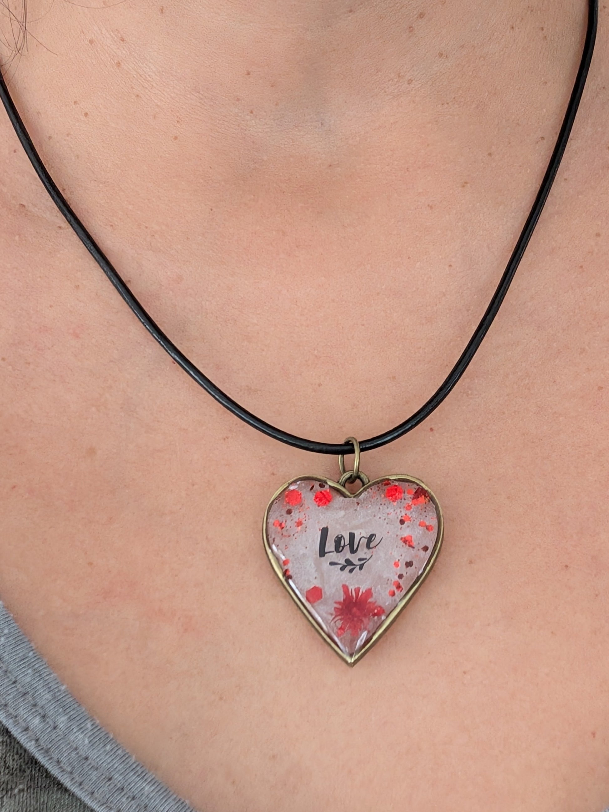 This stunning necklace features an 18 inch black leather cord with a resin and flowers bronze heart pendant. The extension chain allows for a customizable fit. Weighing only 0.2 oz, it's a lightweight and stylish addition to any outfit. Show your love and creativity with this unique necklace.