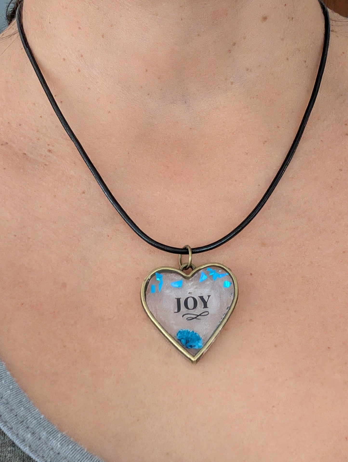 This stunning necklace features an 18 inch black leather cord with a resin and flowers bronze heart pendant. The extension chain allows for a customizable fit. Weighing only 0.2 oz, it's a lightweight and stylish addition to any outfit. Show your love and creativity with this unique necklace.