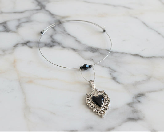 This elegant memory wire choker combines timeless style with modern sophistication. Featuring a striking black stainless steel heart pendant accented with lustrous black beads, it adjusts perfectly to fit neck sizes 4 to 4.5 inches. The durable .025" wire construction ensures lasting wear without losing its shape, while the lightweight design at just 0.28 oz makes it comfortable for all-day elegance. Whether layered with other pieces or worn solo, this versatile choker adds an instant touch of charm to any 