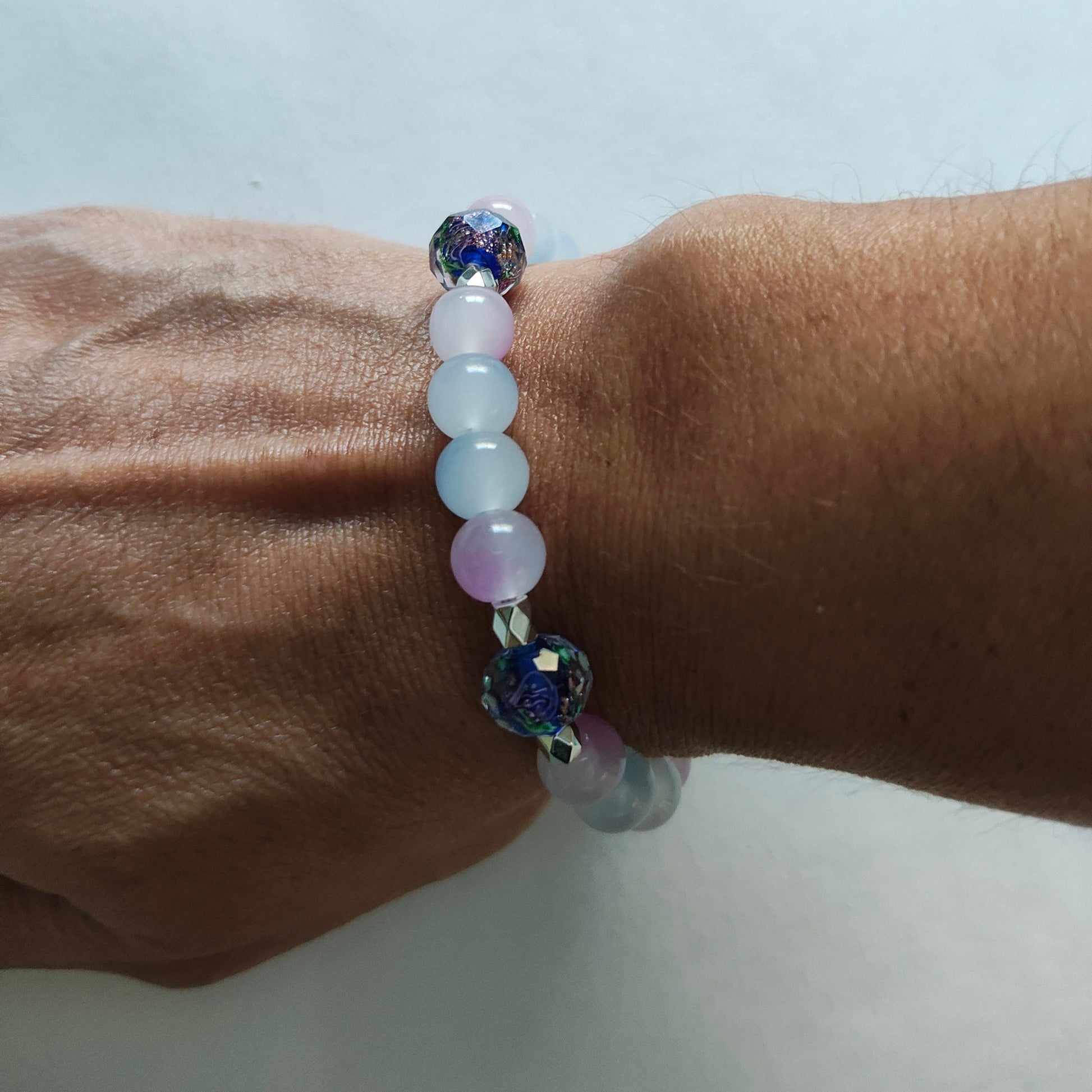 This midnight blue bracelet features beautiful rose gold sand lampwork beads, paired with vibrant 8mm blue and pink glass beads and silver spacer beads. The elastic design allows for a comfortable fit and easy on/off. Elevate any outfit and make a statement with this unique and stylish accessory!