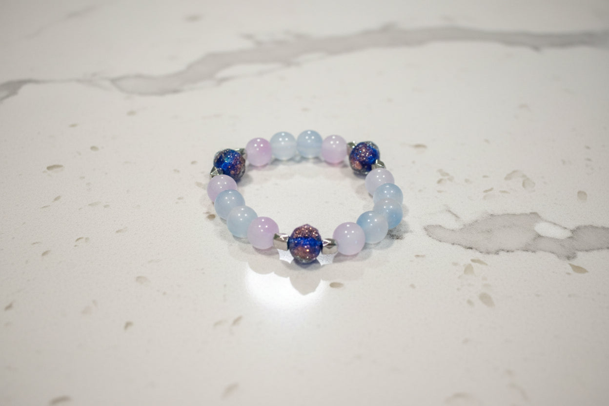 This midnight blue bracelet features beautiful rose gold sand lampwork beads, paired with vibrant 8mm blue and pink glass beads and silver spacer beads. The elastic design allows for a comfortable fit and easy on/off. Elevate any outfit and make a statement with this unique and stylish accessory!
