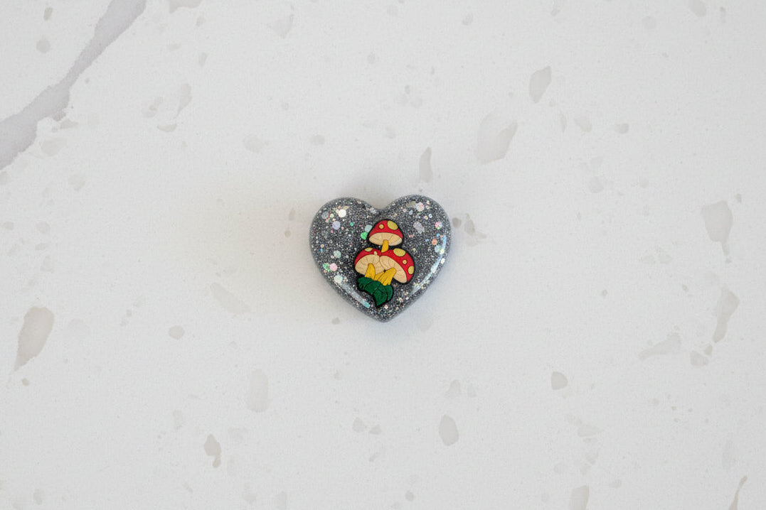 Bring a touch of whimsy to your space with this charming Mushroom Resin Heart Magnet. Perfectly sized at 1.75 x 2 inches, this lightweight magnet (just 0.47 oz) features an enchanting mushroom design captured in beautiful resin. Ideal for refrigerators, lockers, or any magnetic surface, it adds personality and a pop of nature-inspired charm to your everyday décor. A delightful gift for mushroom lovers and resin art enthusiasts alike.