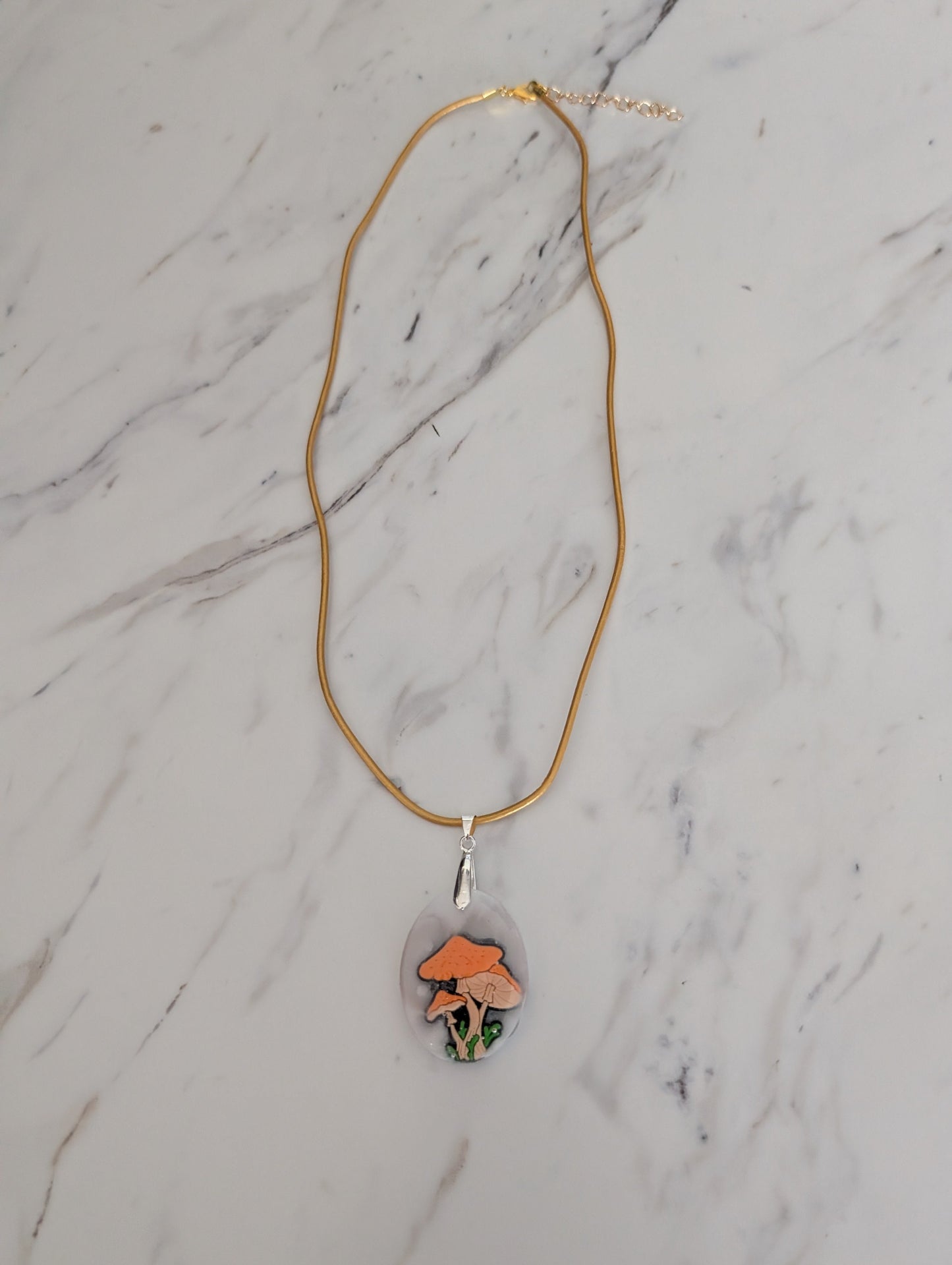 Necklace with a pendant featuring a mushroom design on a marble surface