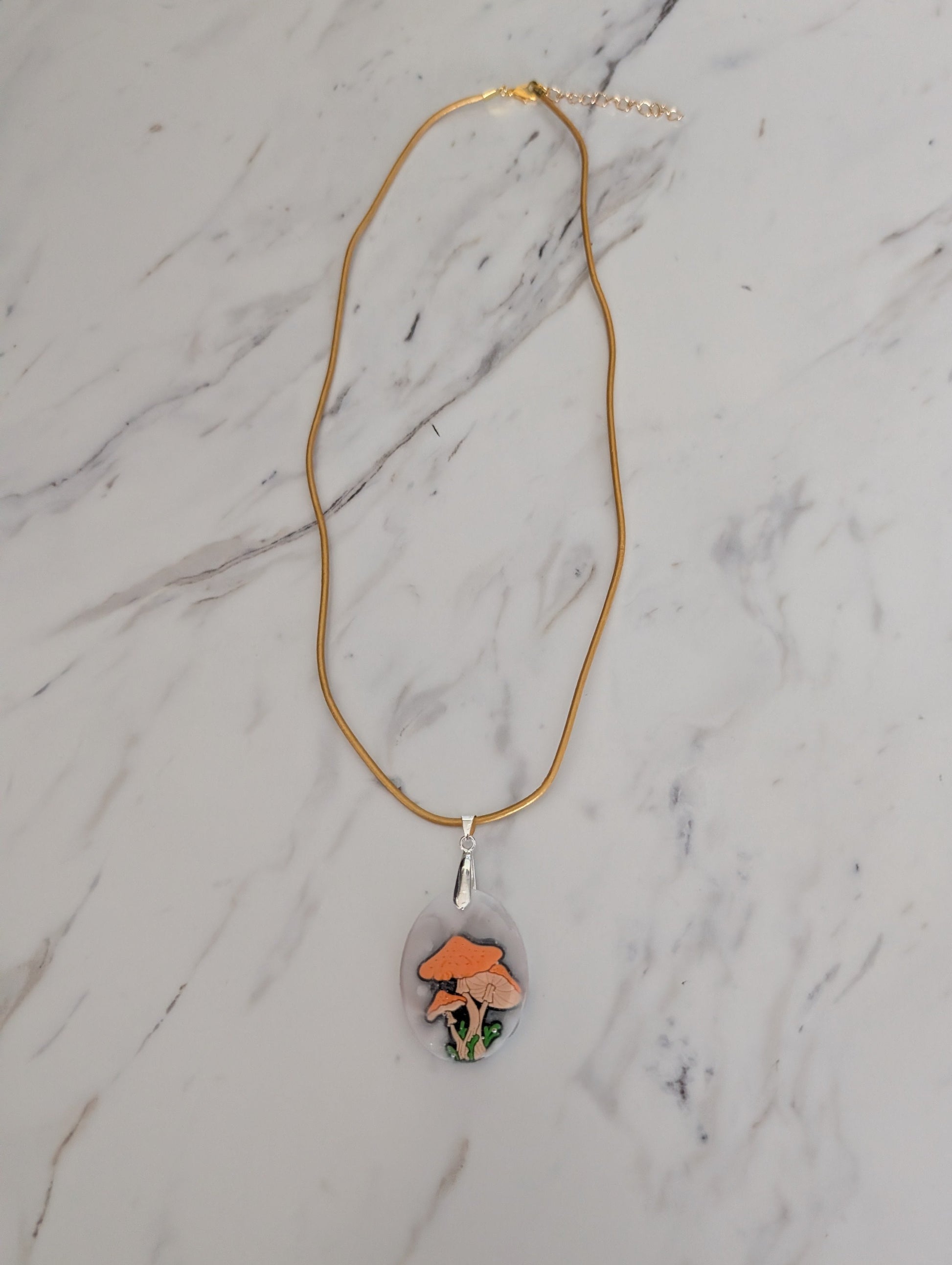 Necklace with a pendant featuring a mushroom design on a marble surface
