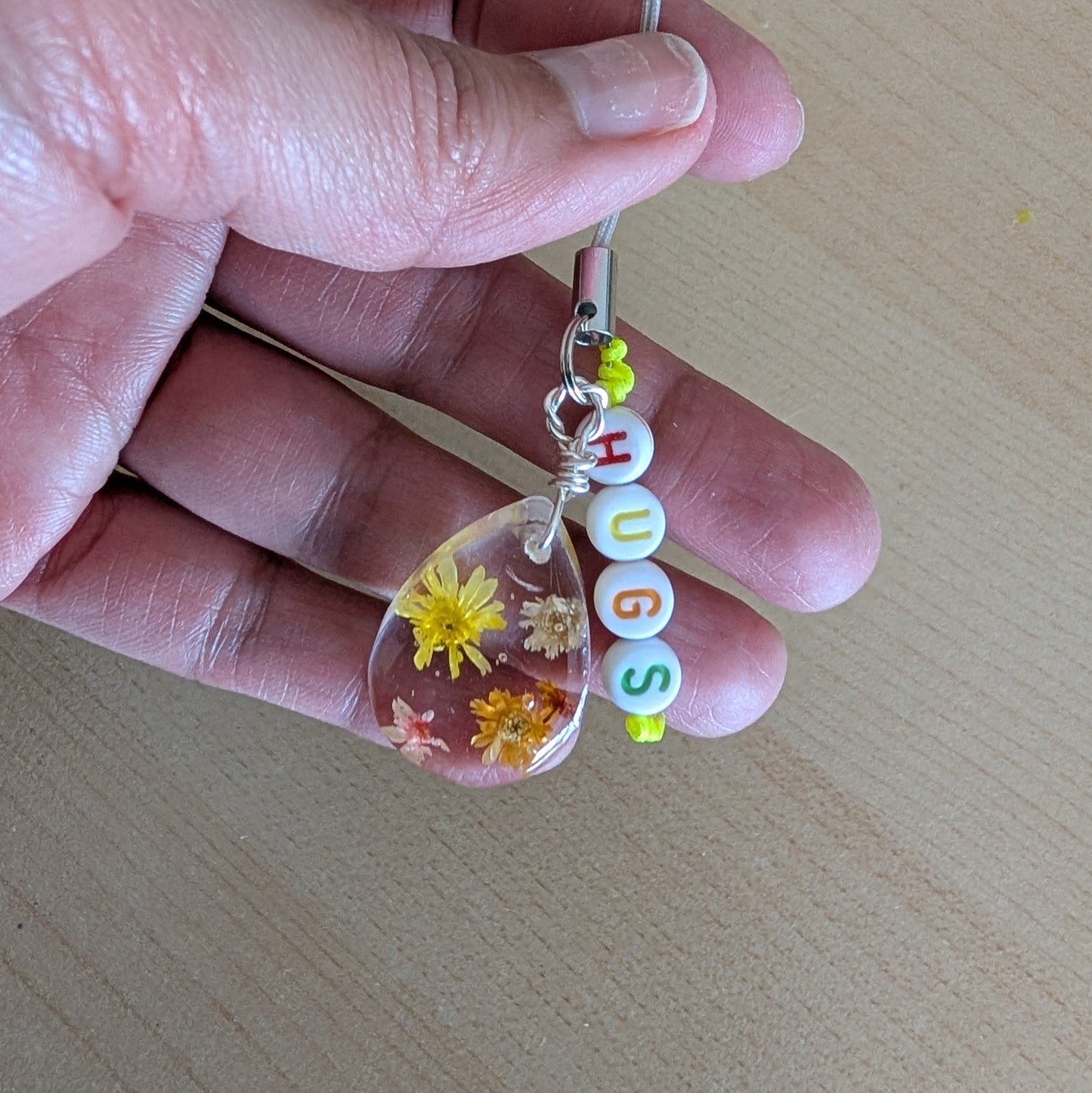 Spice up your phone with this charming resin charm, adorned with real dried flowers and beads. The 3.75 inch length adds a touch of flair to any device. (It's like a bouquet, but for your phone!)