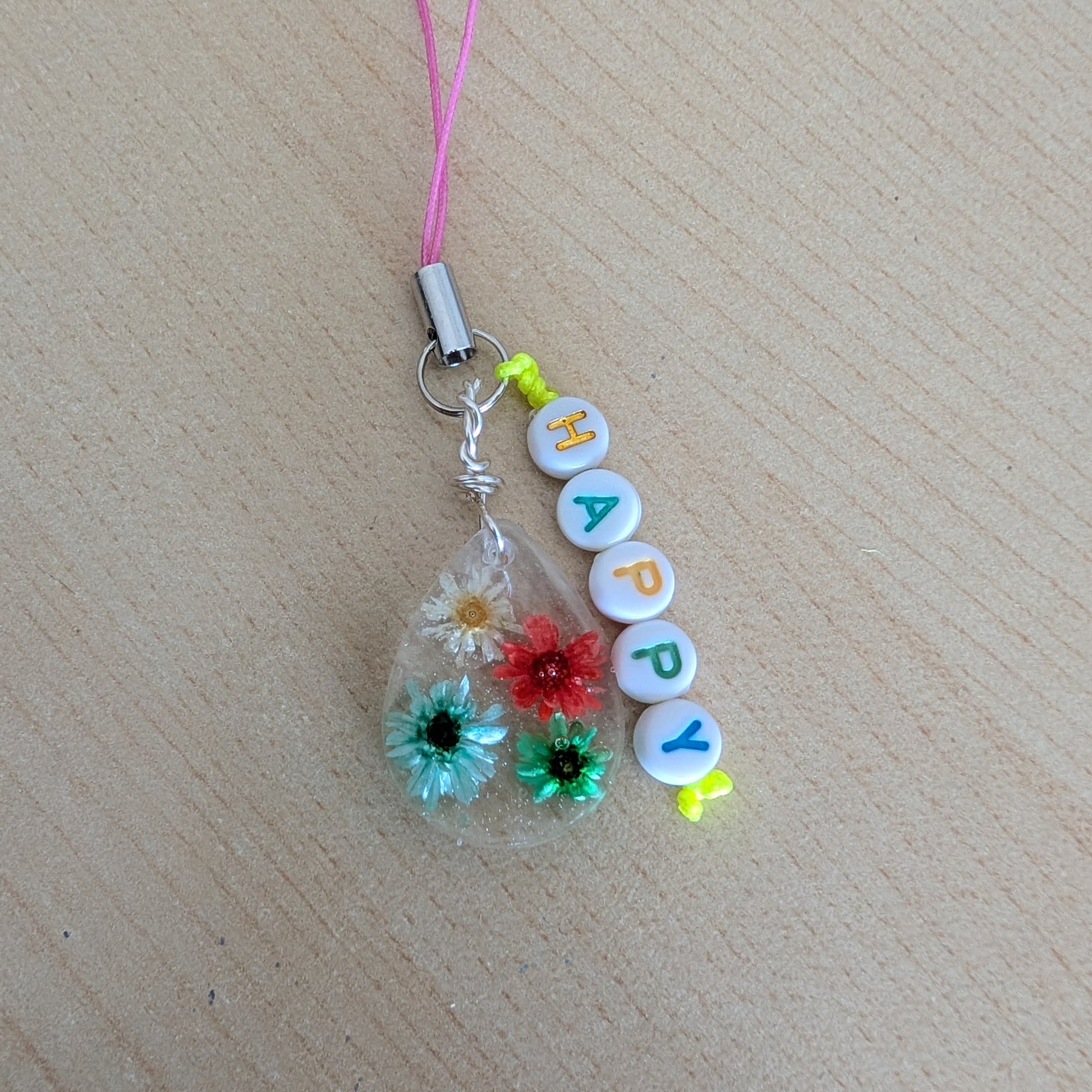 Spice up your phone with this charming resin charm, adorned with real dried flowers and beads. The 3.75 inch length adds a touch of flair to any device. (It's like a bouquet, but for your phone!)