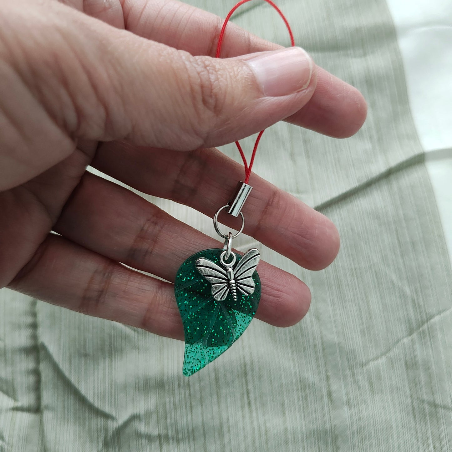 Jazz up your phone with our Phone charm - Resin leaf with butterfly charm! The unique resin leaf design brings a touch of nature to your device, while the playful butterfly charm adds an element of whimsy. At 3.75 inches long, it's the perfect size for on-the-go charm.