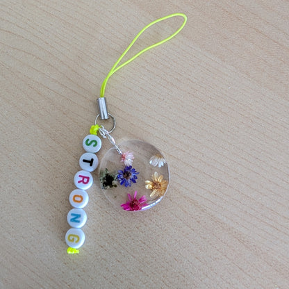 Spice up your phone with this charming resin charm, adorned with real dried flowers and beads. The 3.75 inch length adds a touch of flair to any device. (It's like a bouquet, but for your phone!)

Phone charm - Resin charm with dried flowers and beads