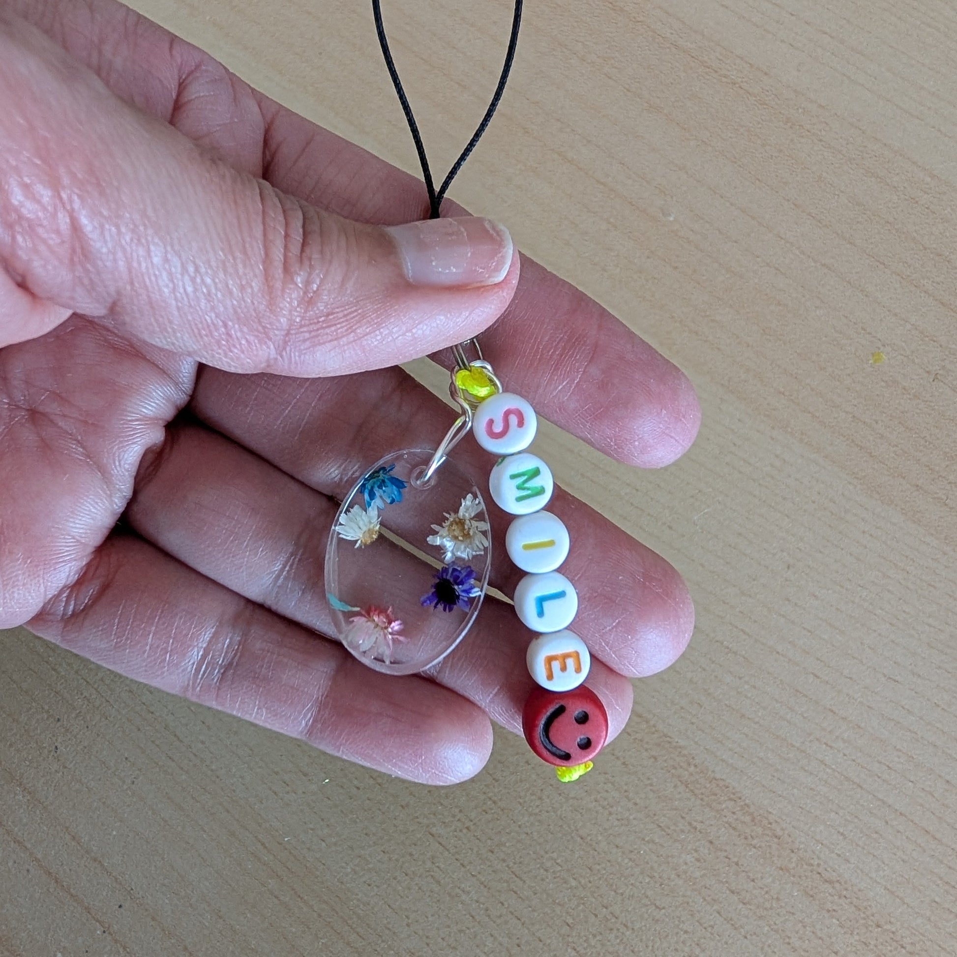 Spice up your phone with this charming resin charm, adorned with real dried flowers and beads. The 3.75 inch length adds a touch of flair to any device. (It's like a bouquet, but for your phone!)