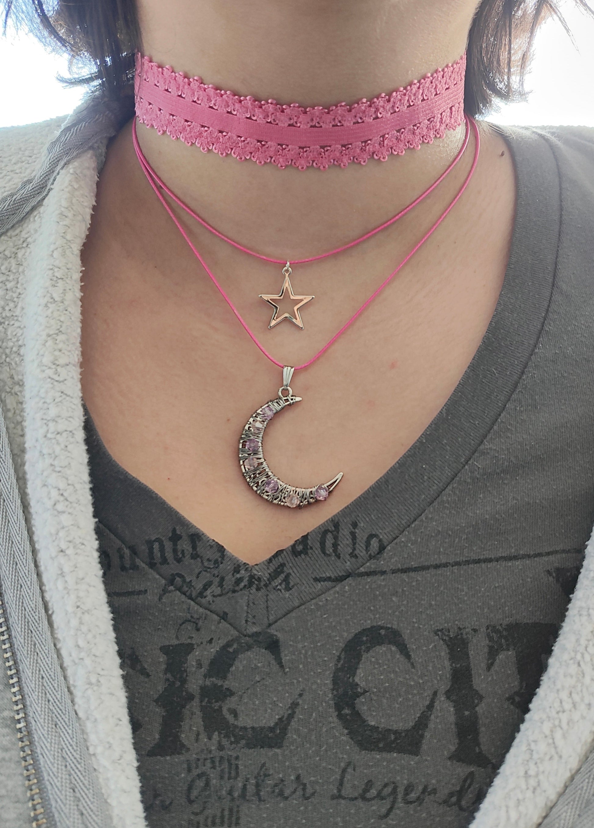 Transform any outfit into a stellar ensemble with this playful Necklace-Choker! Featuring an elastic lace ribbon, two polyester strands, and a crystal-studded silver moon and star charm, this necklace adds a touch of whimsy to your look. Plus, with a 2 inch extension chain, it's perfect for any neckline.