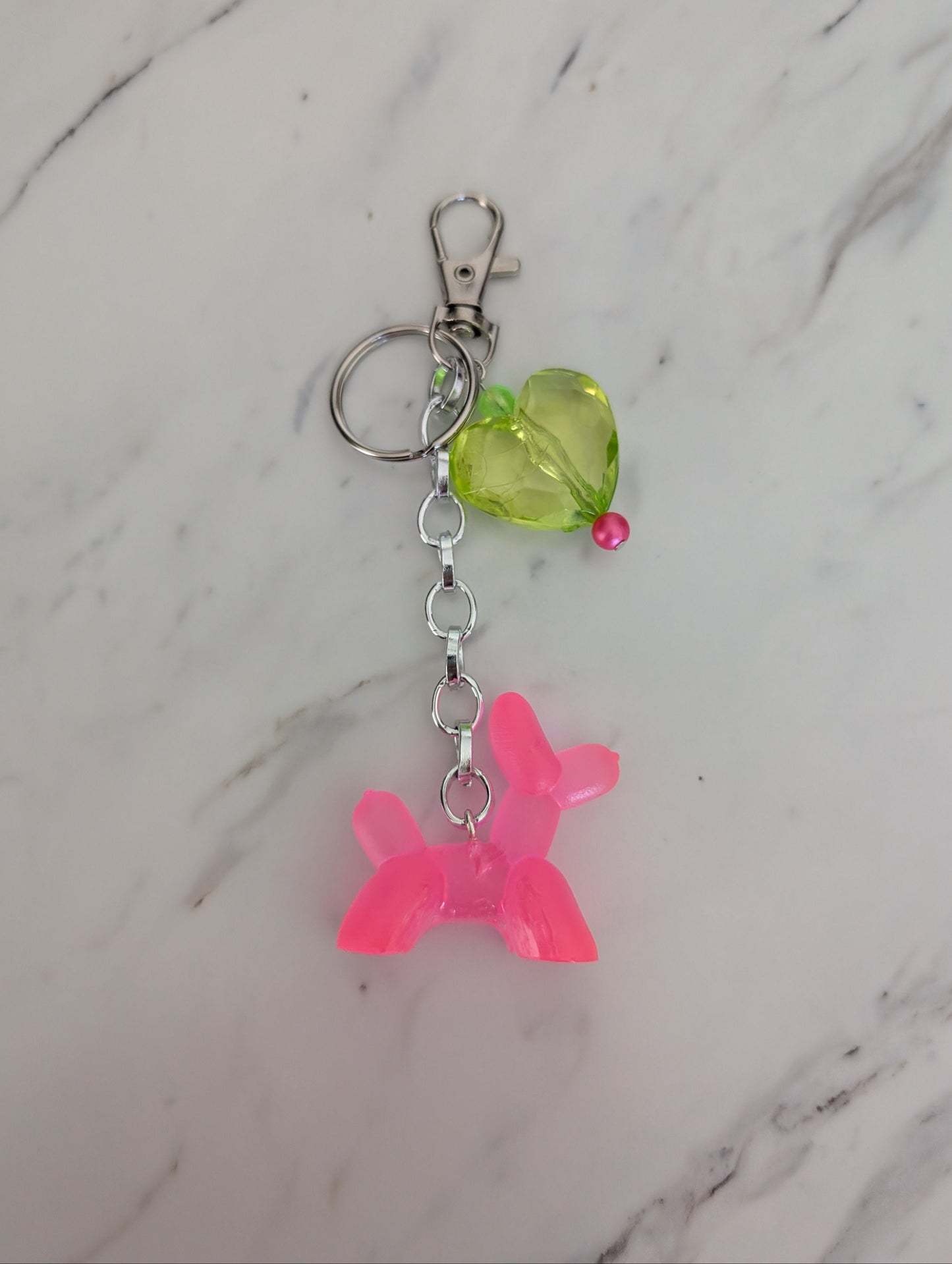 Keychain with pink dog-shaped charm and green bead on a marble background