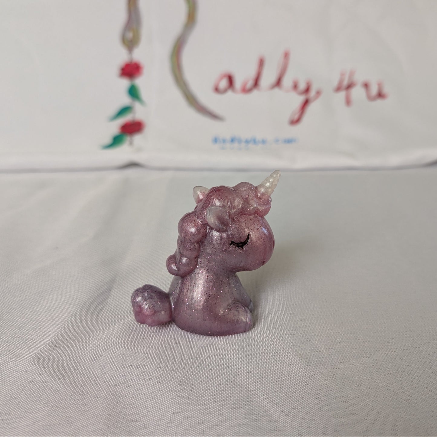 This whimsical resin unicorn is hand-crafted with glossy epoxy resin and detailed with vibrant acrylic paints. Its smooth, glass-like finish captures light beautifully, making it a charming little companion on your desk or shelf.