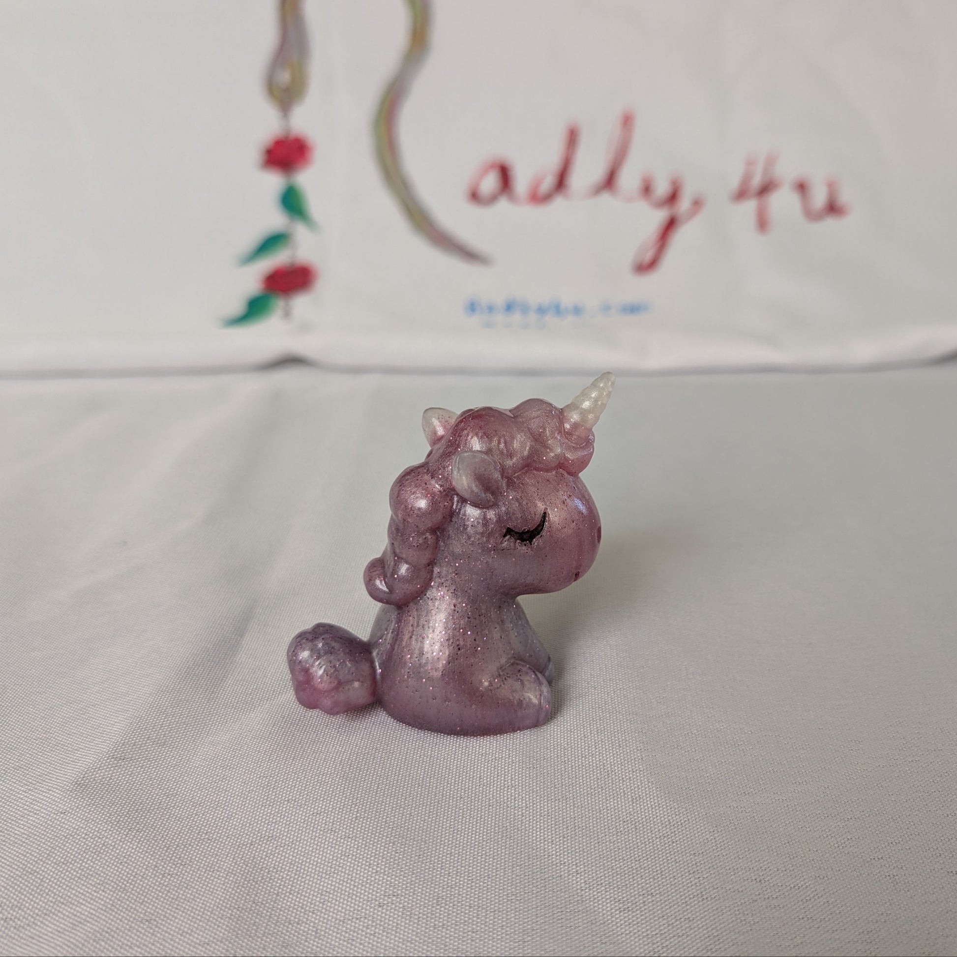 This whimsical resin unicorn is hand-crafted with glossy epoxy resin and detailed with vibrant acrylic paints. Its smooth, glass-like finish captures light beautifully, making it a charming little companion on your desk or shelf.