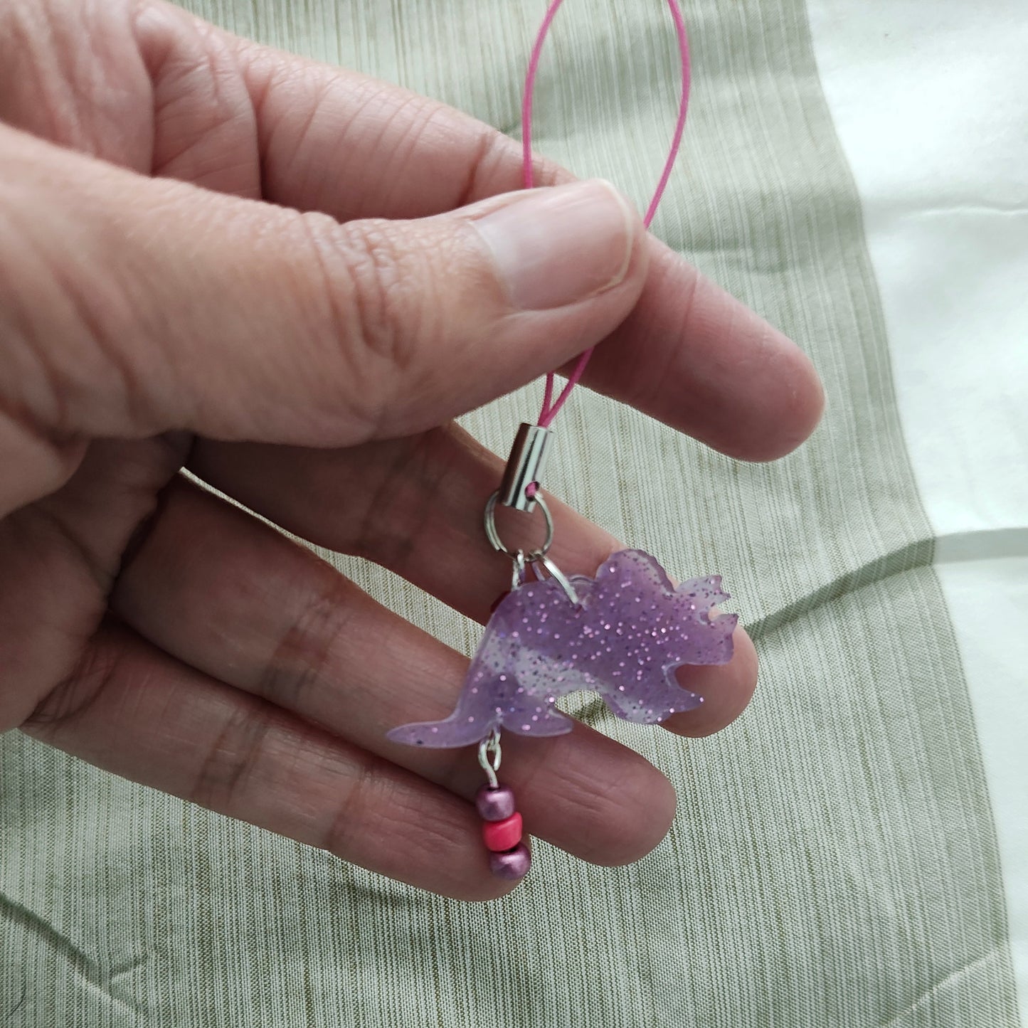 Add some prehistoric charm to your phone with our Triceratops resin dinosaur charm, adorned with colorful beads. Stand out from the herd and protect your phone in style. (No need to be a fossil to appreciate this cute accessory!)