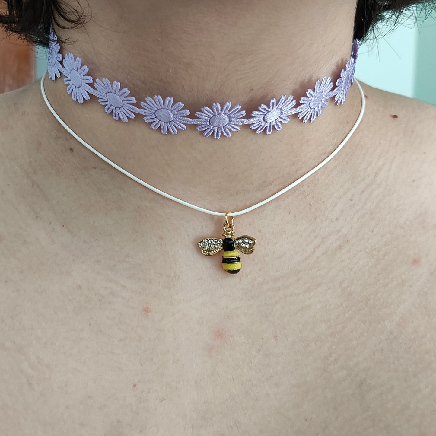 Get ready to make a buzz with this playful purple daisy choker! Featuring a charming bee charm and a trendy ribbon design, this necklace adds a touch of fun to any outfit. And with its durable polyester strand, you can rock this quirky accessory for any occasion.
