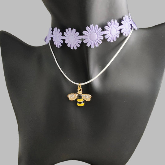 Get ready to make a buzz with this playful purple daisy choker! Featuring a charming bee charm and a trendy ribbon design, this necklace adds a touch of fun to any outfit. And with its durable polyester strand, you can rock this quirky accessory for any occasion.